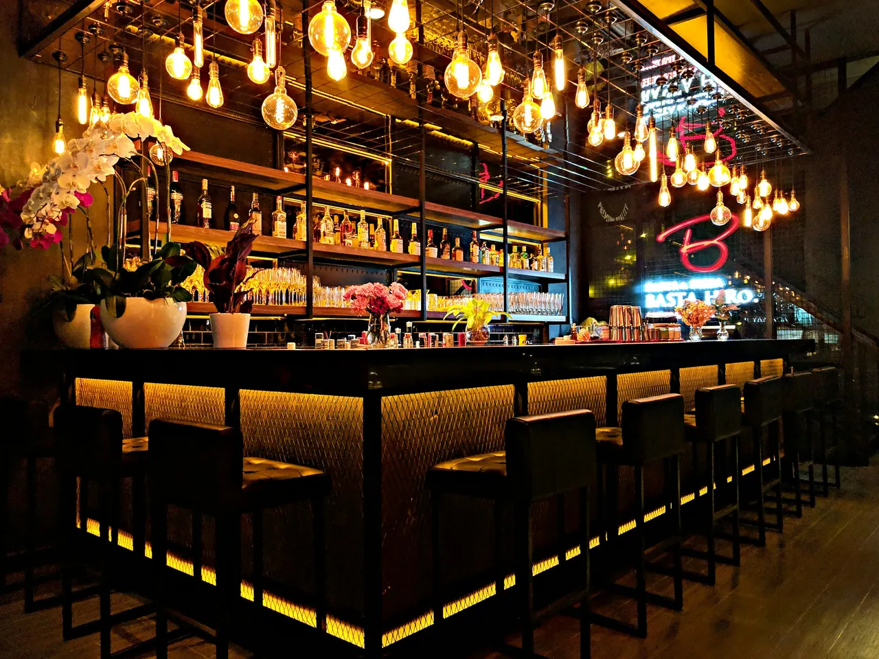 The Night Bar counter lined with bottles and stools under warm lights