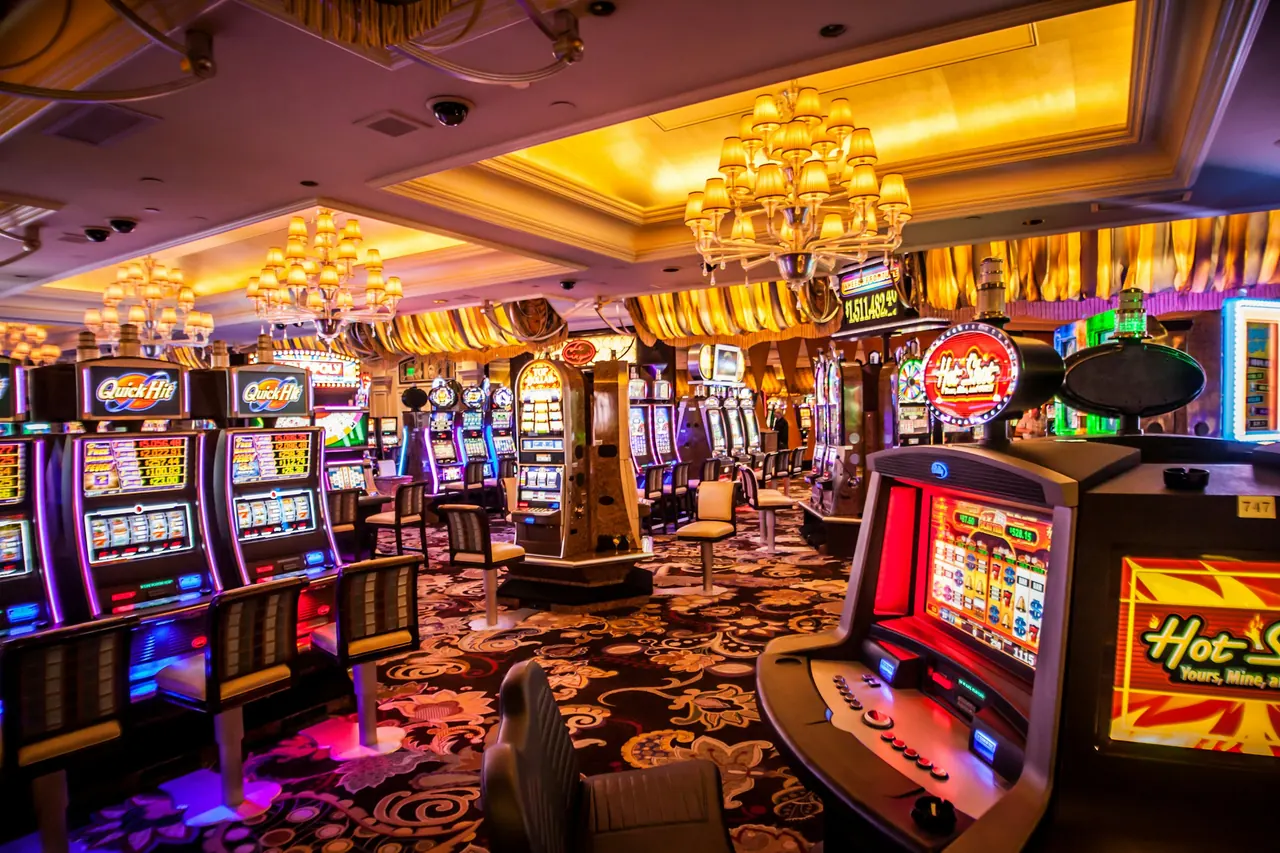 The casino floor beneath chandeliers, with rows of gaming machines and patterned carpet