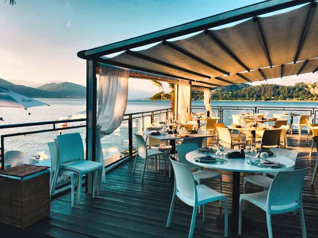 A covered terrace restaurant set for dinner beside the water