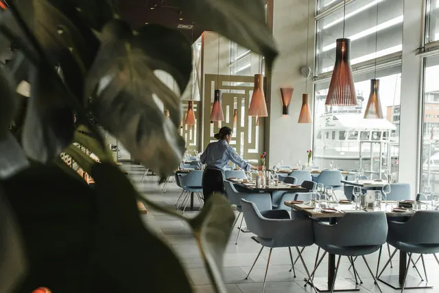 A bright restaurant with set tables beside large windows
