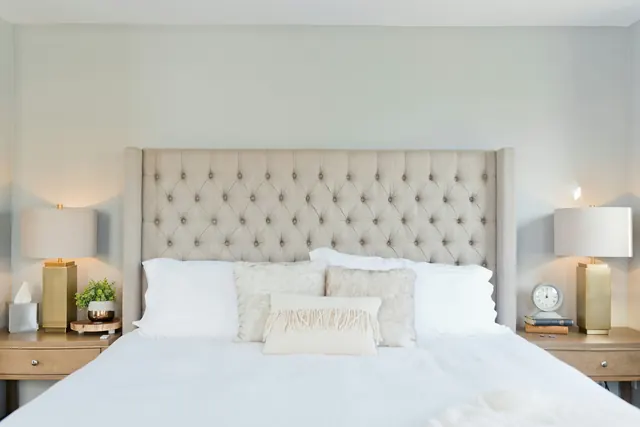 A guest room with a tufted headboard, crisp white bedding and bedside lamps