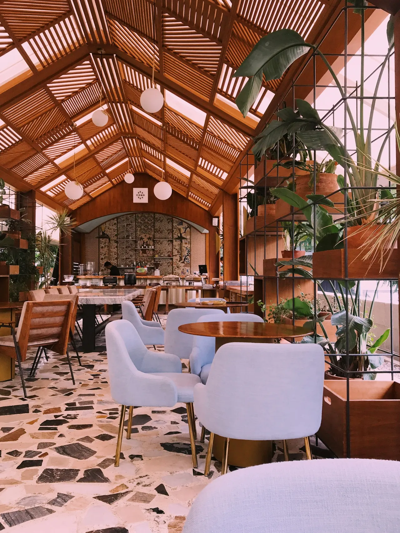 Ember Lounge with armchairs, a timber-beamed ceiling and hanging plants